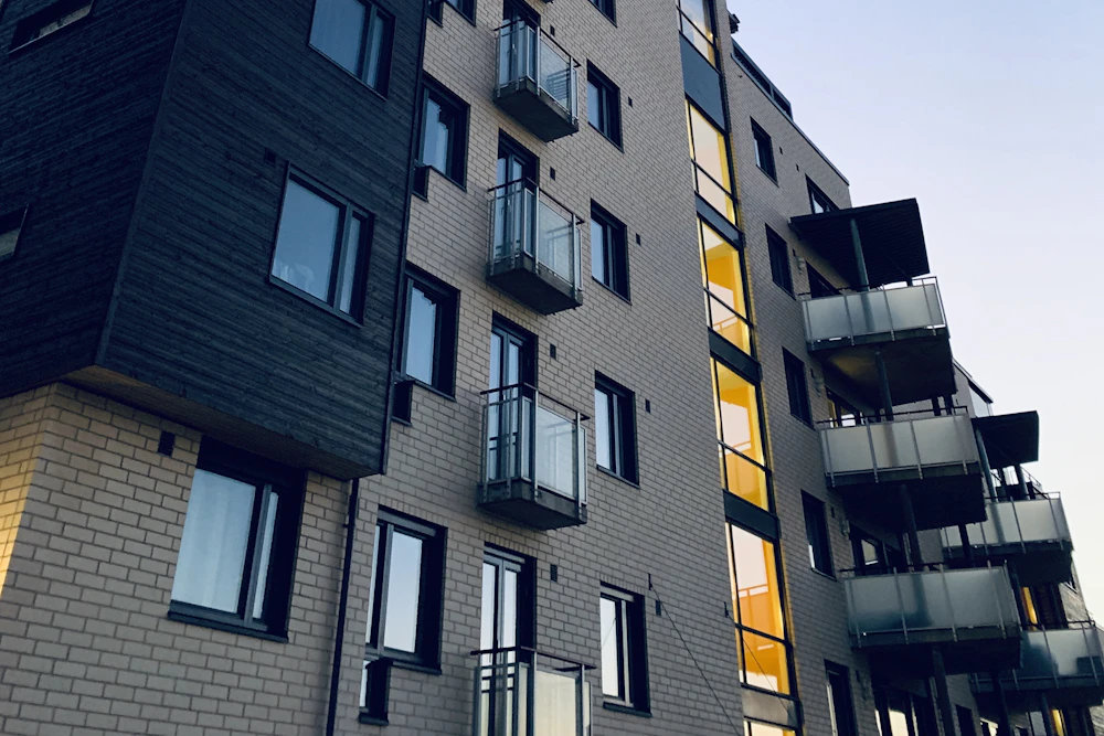Fasaden på ett modernt flerbostadshus med balkonger i kvällsljus