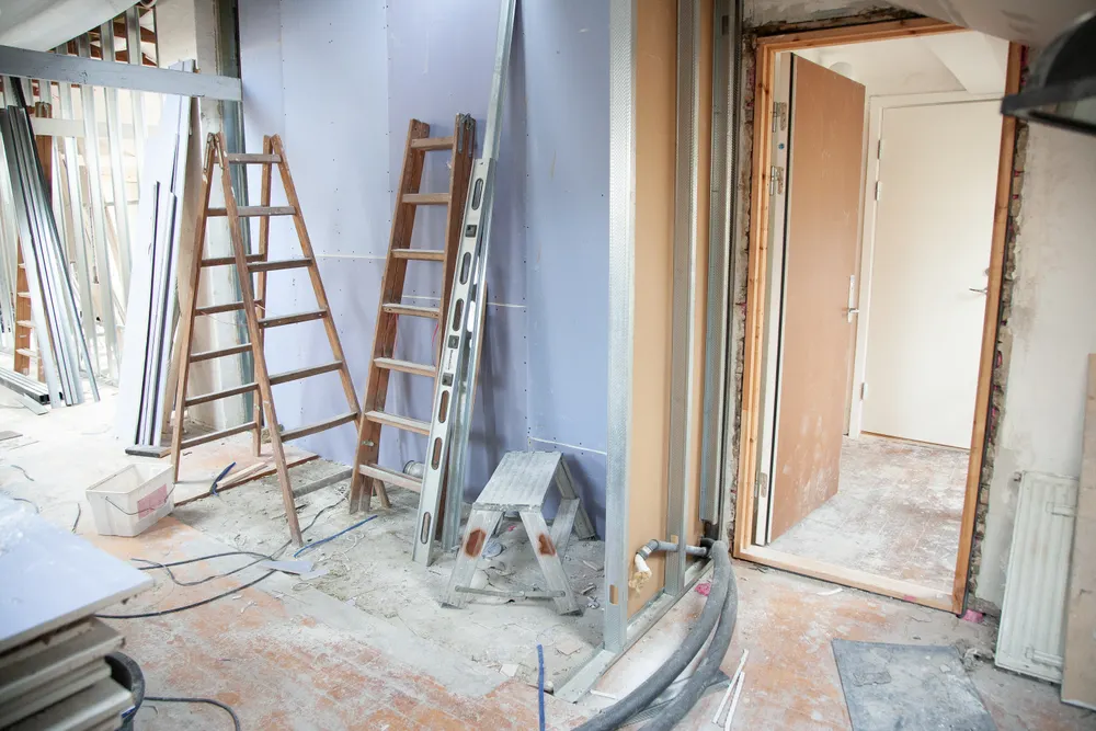 En lägenhet under renovering med stegar och uppriven golvbeläggning
