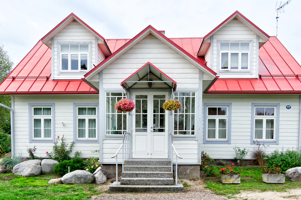 Ett vitt trähus med rött plåttak och glasveranda