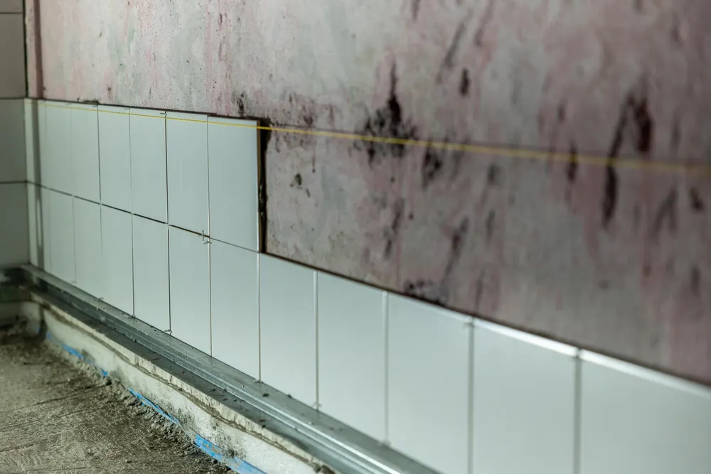 Ett våtrum under arbete där kaklet är delvis uppsatt och tätskiktet bakom syns